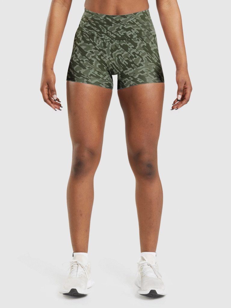 Woman wearing high-waisted green camouflage athletic shorts with a seamless fit, paired with white training sneakers.